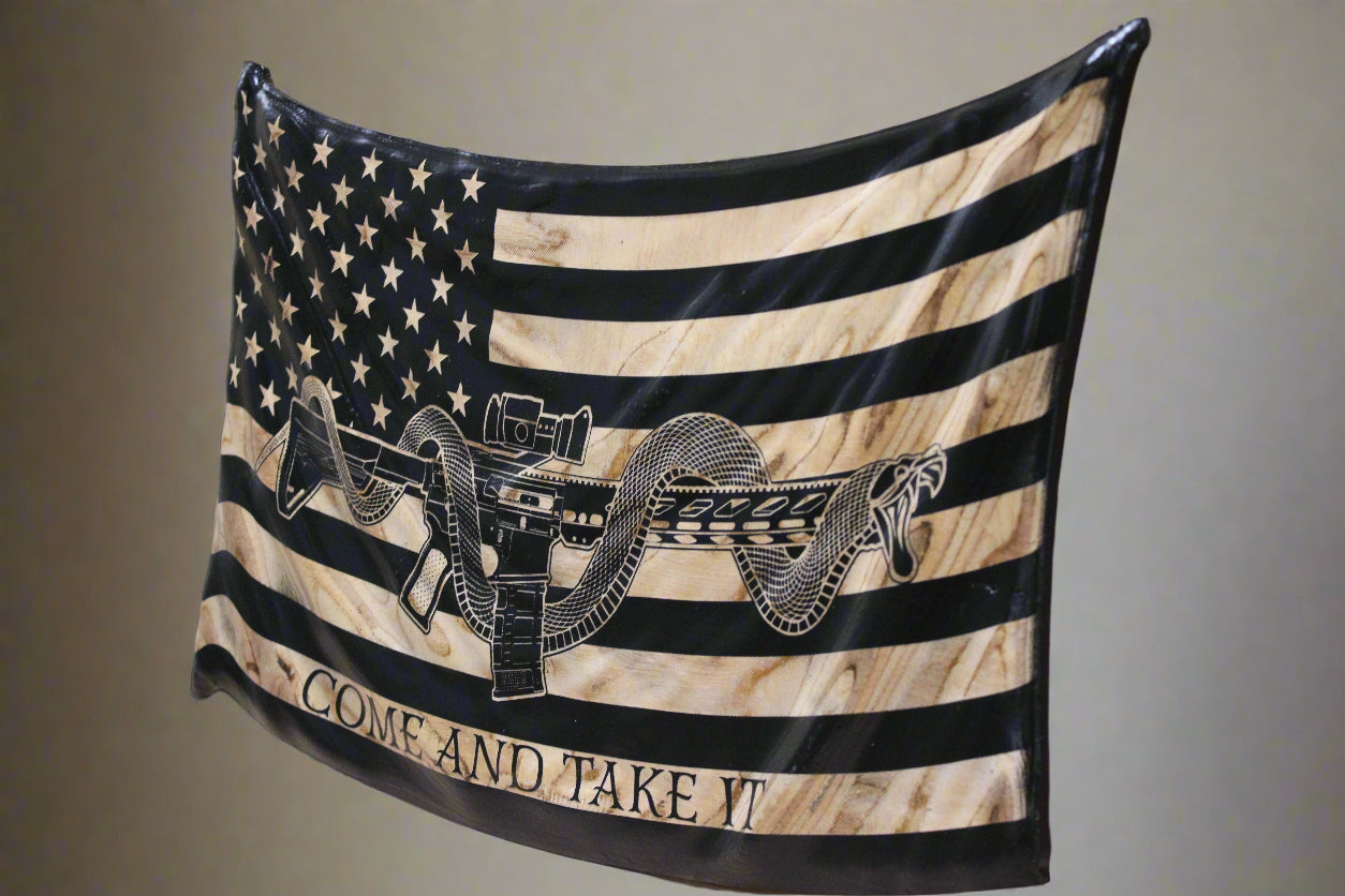Detailed carving of M4 rifle & coiled snake on wavy “Come and Take It” wooden flag
